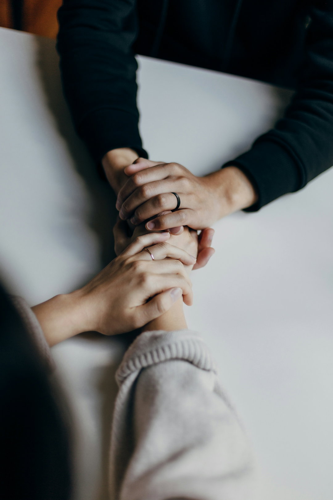 two-people-holding-hands-on-table-in-comfort.jpg two people holding hands on table in comfort